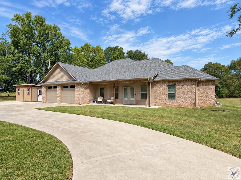 A brick home with a curved driveway and mature trees in Bowie County